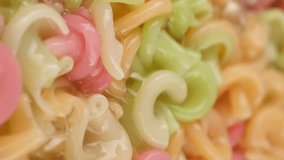 Multi color pasta for kids boiled in boiling hot water on pan. Vertical video