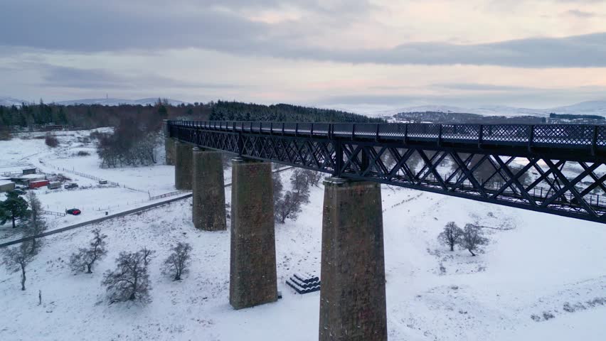 Flying above Findhorn Viaduct as a flock of sheep gather in the snow covered field