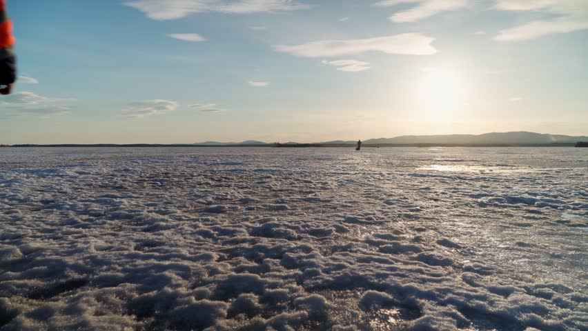 Two fisherman friends go winter fishing. Fishermen move on the ice of a frozen lake on a clear sunny day.