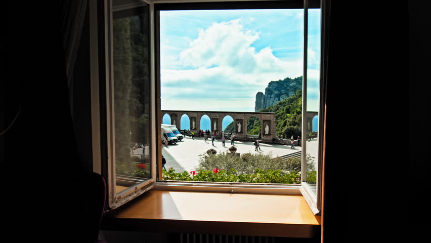 Beautiful Hotel view through the window of the Montserrat mountain village town. A resort view of Tourists exploring Montserrat main square a mountain range near Barcelona, in Catalonia, Spain.