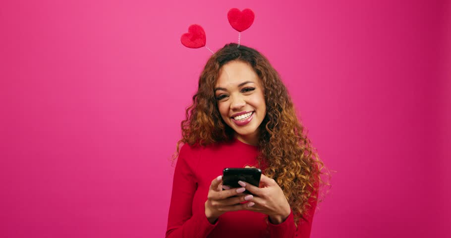 Beautiful young woman texts and smiles to camera, Valentines Day, dating app