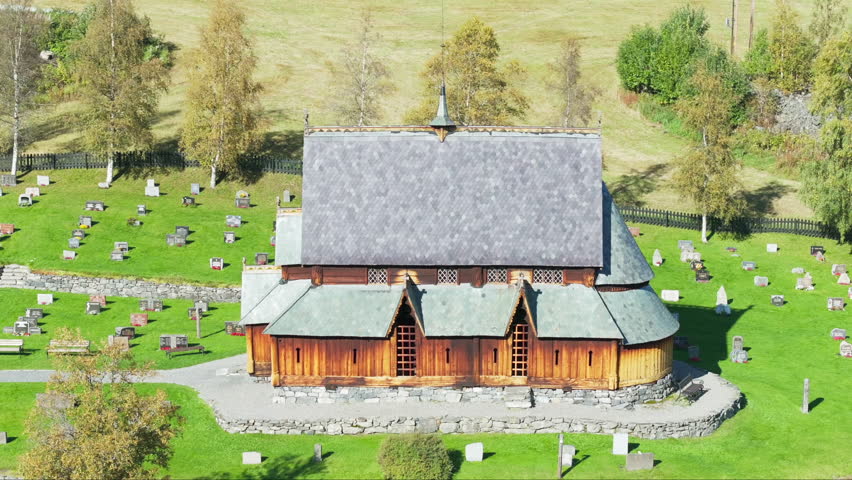 Ancient wooden Norwegian stave church with graveyard in Valdres; drone orbit