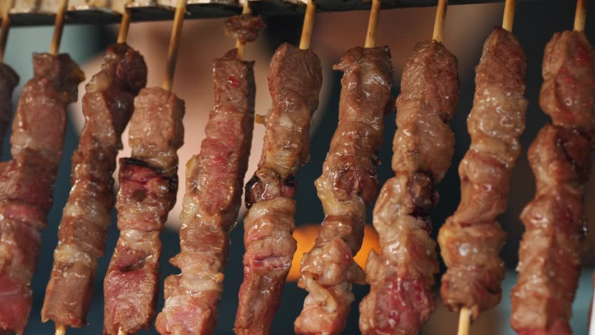 Rotating fried meat on a skewers. shashlik or Shish Kebab. close-up.Cooking juicy pork meat on metal skewers in electrical barbecue grill.  Royalty-Free Stock Footage #1109815357