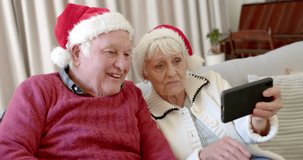 Senior caucasian couple wearing santa hats using smartphone for christmas video call, slow motion. Senior lifestyle, communication, christmas, celebration and domestic life, unaltered.