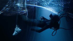 Beautiful woman with flowing hair in futuristic dress under the water. Girl in glasses of virtual reality. Augmented reality, game, future technology concept. VR.