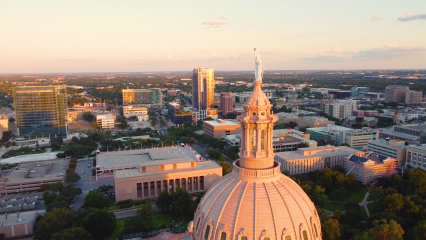 Downtown Austin, Texas State Capital Building, Aerial Drone Shot Flying Around Goddess of Liberty Statue on Top with Views of The University of Texas at Austin Campus Skyline at Sunset in 4K.
