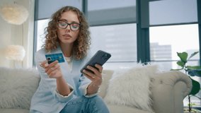 Smart stylish woman in protecting eye glasses holding smartphone and credit card at modern home. Happy female shopper using instant easy mobile payments, customer making purchase in online store app - Powered by Shutterstock - Get 15% off with code: PIKWIZARD15