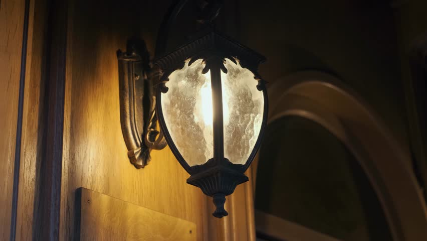Vintage electric lantern hanging at the entrance of a building with wooden decoration