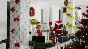 Happy multiethnic team working on christmas season in decorated office. Cheerful employees solving tasks at desk in diverse workplace next to colleagues during winter festive time - Powered by Shutterstock - Get 15% off with code: PIKWIZARD15