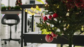 Jib up close up shot of beautifully ornate Christmas pine tree with empty office in blurry background. Xmas tree adorn with red garlands and baubles in festive workspace during winter holiday season - Powered by Shutterstock - Get 15% off with code: PIKWIZARD15