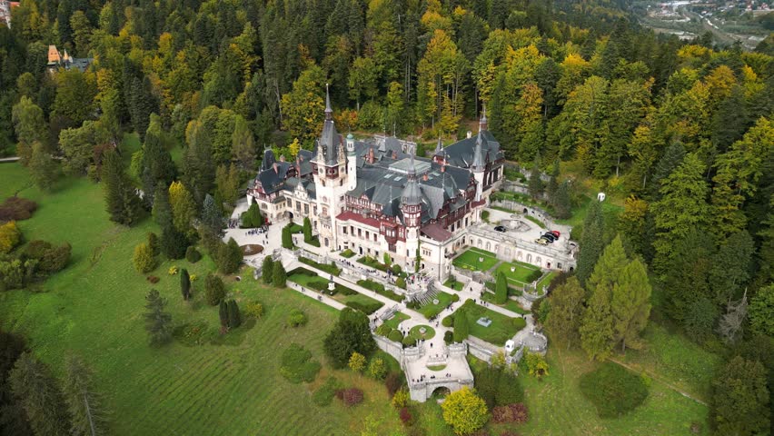 Drone video of Peles Castle in Sinaia during autumn. Panoramic and scenic video of Peles Castle. Castle with gardens and tourists in Carpathians mountain. Romania