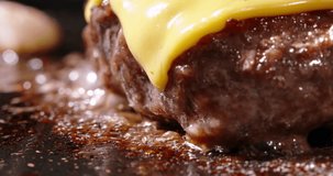 Macro shot of frying beef halal cutlets with melted cheese on top. Cinematic advertisement burger cooking. Video of cutlets frying in pan, advertisement of burger, cooking cheeseburger. Fat high
