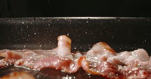 Frying halal beef bacon in pan side view close up slow motion. Process of frying bacon in pan. Meat bubbling in hot fat. Bacon ultimate crispy, crunchy, and savory delight. Fried to perfect. Fat