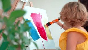 Teacher At Art School Helping Children in Art Class with painting. Woman teaches child to create and work with acrylic paint. Group of primary school kids learning how to draw and color help of their - Powered by Shutterstock - Get 15% off with code: PIKWIZARD15