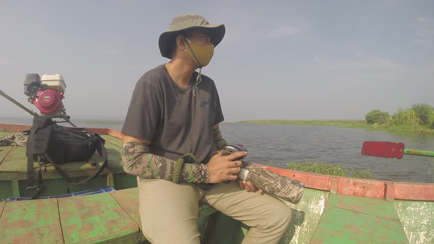 A bird and wildlife photographer clicking photos from a boat with a Canon DSLR camera and telephoto lens