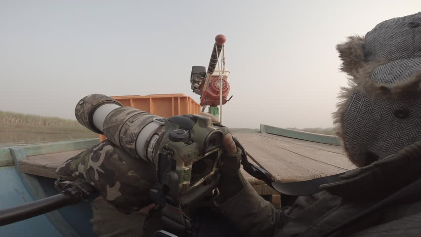 A bird and wildlife photographer clicking photos from a boat with a Canon DSLR camera and telephoto lens