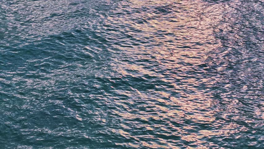 View of the sea surface with reflected sunlight. Turquoise water ripple background texture. Waves of the Caribbean Sea on a bright sunny day. Bird's-eye. Sunset ocean background.