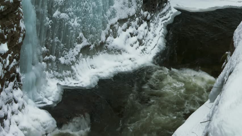 Iced covered gorge cliff and flowing river, Ausable Chasm in Adirondacks