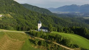 Scenic view of St. Primoz Church in Jamnik, Slovenia, on a sunny summer day, captivating alpine landscape