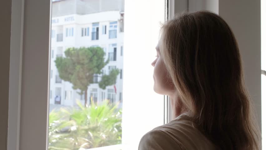 closeup of woman waking up and stretching in the morning in hotel room by the window