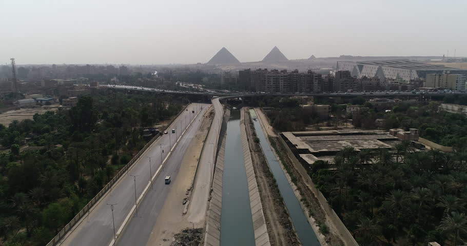 Aerial Shot for The Pyramids of Egypt in Giza beside a branch from the River Nile in the foreground Maryotya branch