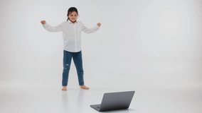 A little girl is dancing, online video chatting with a laptop, a child is dancing in front of a laptop camera. Children's distance sports and dance classes, children's sports sections online.