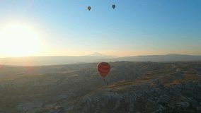 In this aerial video, the skies above Cappadocia, Turkey, come alive with a kaleidoscope of hot air balloons. Against the backdrop of the region's iconic valleys, rocks, and fields, this mesmerizing