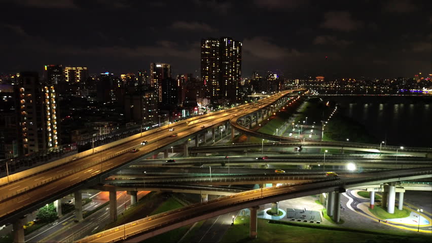 Aerial 4k video of Xinbei Bridge at night. Cars pass through the bridge with colorful lights. New Taipei City, Xindian Sunshine Sports Park Sunshine Bridge.