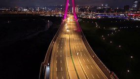 Aerial 4k video of Xinbei Bridge at night. Cars pass through the bridge with colorful lights. New Taipei City, Xindian Sunshine Sports Park Sunshine Bridge.