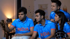 A pan shot of four Indian friends huddled together, watching a crucial cricket match on a smartphone, serious and tense expressions. Indian cricket team fans are engrossed in a match being broadcast - Powered by Shutterstock - Get 15% off with code: PIKWIZARD15