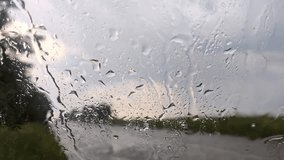 Raining on glass windscreen window, water drops close-up with cloudy blurred background. Moody rainy footage on rural road - Powered by Shutterstock - Get 15% off with code: PIKWIZARD15