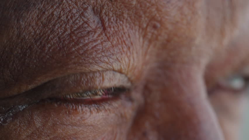 African American eye macro close-up. A black older person opening blue eyes awakening