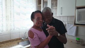 African American couple dancing together in kitchen, romantic moment between a black elderly husband and wife holding hands feeling happy - Powered by Shutterstock - Get 15% off with code: PIKWIZARD15