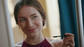 Smiling model applying mascara on eyelashes closeup. Attractive girl admiring mirror reflection doing romantic makeup at home. Gorgeous young lady getting ready in evening. Visage femininity concept. - Powered by Shutterstock - Get 15% off with code: PIKWIZARD15