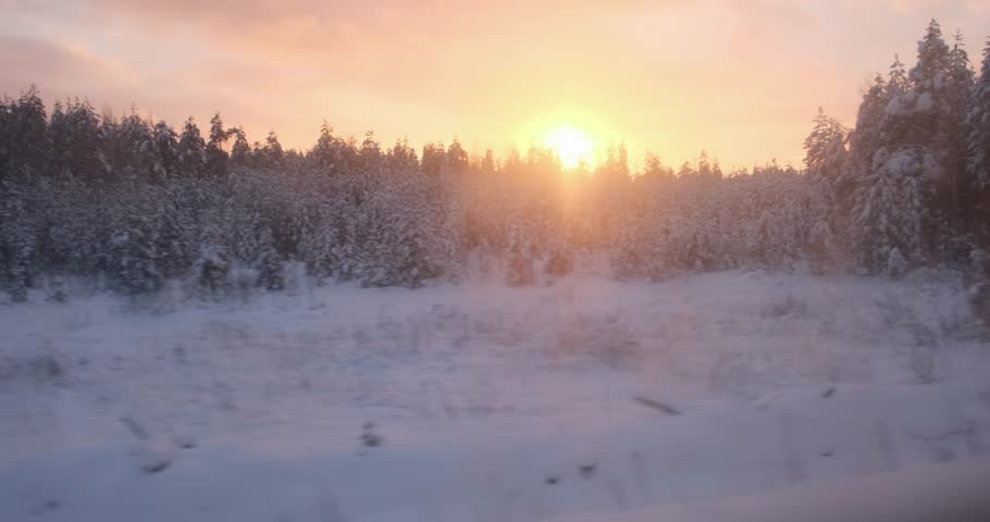 As the sun dips, the train provides a panoramic view of woods, their snowy landscape illuminated by the fading light.