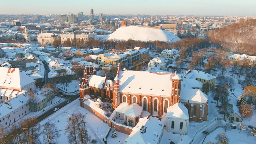 Aerial view of St. Anne's Church and neighbouring Bernardine Church, one of the most beautiful and probably the most famous buildings in Vilnius. Beautiful winter day in the capital of Lithuania. Royalty-Free Stock Footage #1109876987