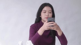 Young Asian Student woman talking over smartphone or cellphone having phone conversation listen at her desk indoors house