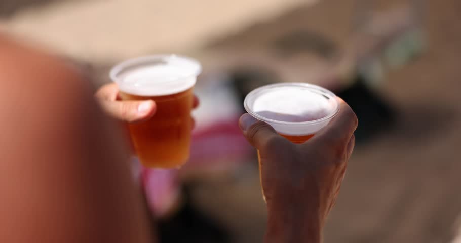 Man hands carry two glasses of cold fresh beer on beach. Refreshing summer drink