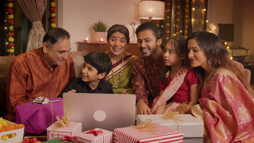 Happy smiling Hindu ethnic Indian family group members in traditional attire interacting on video call with distant relatives using a laptop on a Diwali festival. communication,  connectivity concept. | Shutterstock HD Video #1109881937