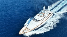 Aerial drone tracking video of latest technology mega yacht with wooden deck cruising deep blue Mediterranean sea