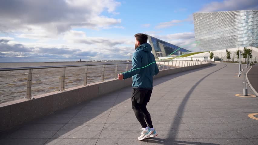 Uses a skipping rope man warm-up cardio workout jumps on the spot intense workout. Motivation a person who trains an active lifestyle. Slow motion video.