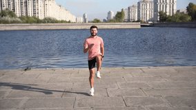 Active exercises in one place, the instructor is a healthy athletic man running in running shoes and sportswear for training. Athlete intensive workout warm-up in the city. Slow motion video.