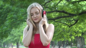 young woman using headphones  listening to music close eyes relaxing  in garden park