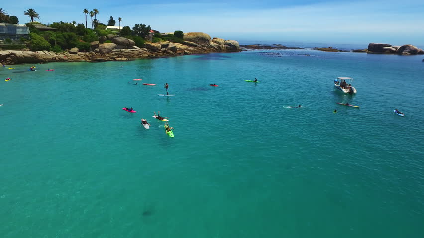 Sea, surfing and drone of people on holiday, tropical vacation or summer travel outdoor in Cape Town South Africa. Ocean, aerial view and crowd in water sports, group swimming and boat in seascape
