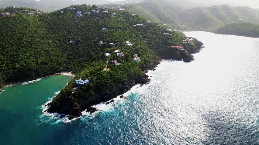 Amazing aerial view of St. Thomas USVI houses on hill mountain blue turquoise water crashing on rocks white foam sun gleaming in water