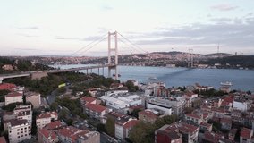 Drone video of Bosphorus in Istanbul during sunset. First and second bridge filmed from above. Turkiye flag waving. Ships passing under the bridge.