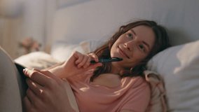 Dreamy girl writing notebook in bed. Inspired woman resting home making notes in diary journal. Smiling pensive female lying comfortable pillows planning day weekend. Romantic model sharing thoughts - Powered by Shutterstock - Get 15% off with code: PIKWIZARD15