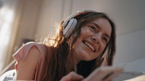 Carefree girl listening headphones music closeup. Smiling woman browsing mobile phone having fun at home. Joyful beautiful female enjoying free time typing smartphone message. Happy teenager lifestyle - Powered by Shutterstock - Get 15% off with code: PIKWIZARD15