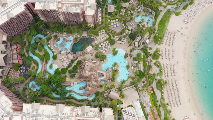 Aerial view of beachfront hotel at cinematic beautiful clear blue lagoon on Oahu island. Family hotel at Ko Olina resorts on Hawaii USA. People enjoying summer vacation on exotic green paradise island