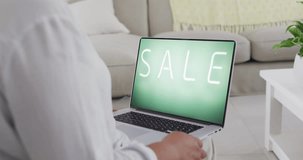 Biracial woman using laptop at home online shopping during sale, slow motion. Retail business, sale, communication and digital interface digitally generated video.